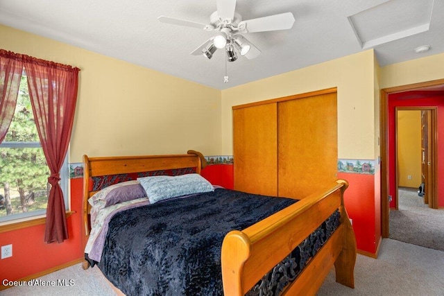 bedroom featuring a closet, light colored carpet, and ceiling fan