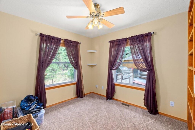 empty room featuring ceiling fan, a healthy amount of sunlight, and light colored carpet