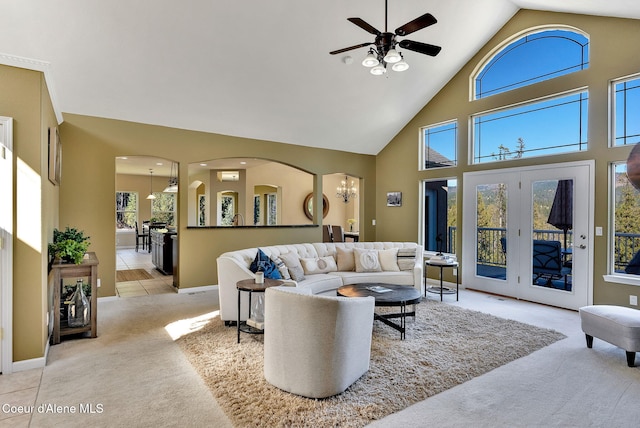 carpeted living room featuring french doors, a towering ceiling, and ceiling fan with notable chandelier