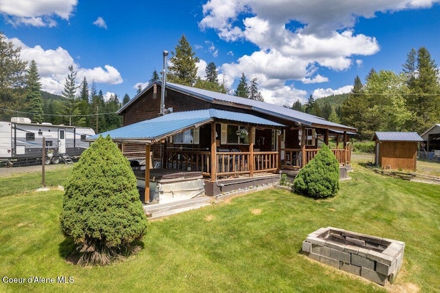 back of property featuring an outdoor fire pit, a lawn, and a storage shed