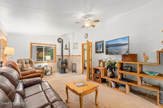 carpeted living room featuring lofted ceiling, ceiling fan, and a wood stove