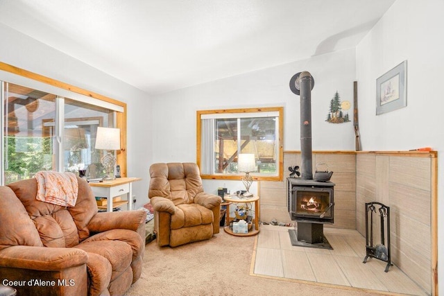 living room featuring vaulted ceiling, carpet floors, and a wood stove