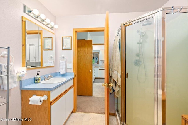 bathroom featuring a shower with door and vanity