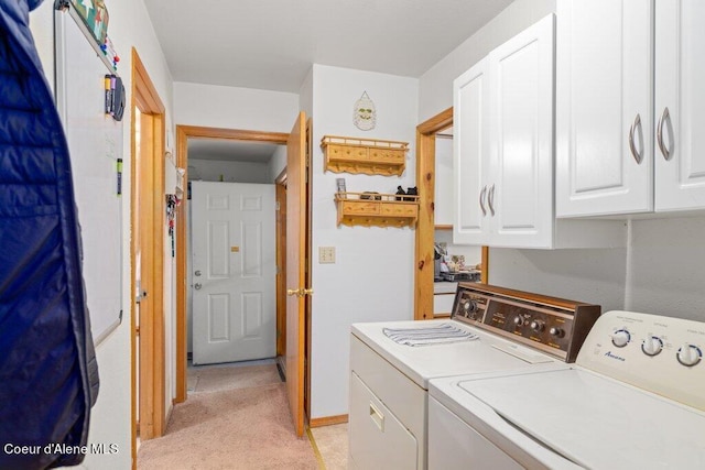 clothes washing area featuring washing machine and dryer, light carpet, and cabinets