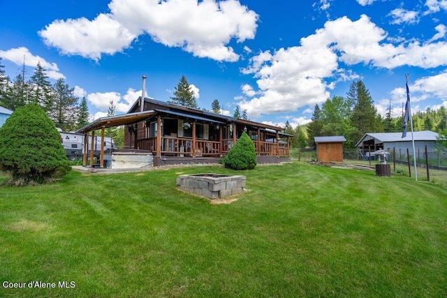 back of property featuring a fire pit, a yard, and a shed