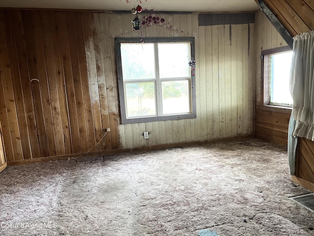 unfurnished room with a wealth of natural light and wooden walls