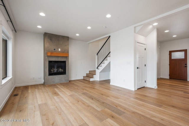 unfurnished living room featuring a fireplace, a healthy amount of sunlight, and light wood-type flooring