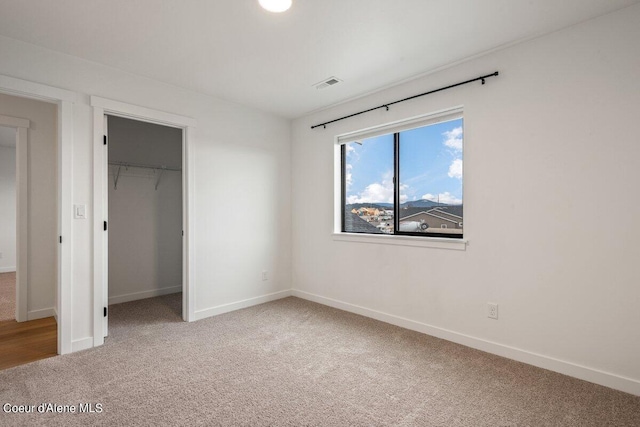 unfurnished bedroom featuring carpet floors, a spacious closet, and a closet