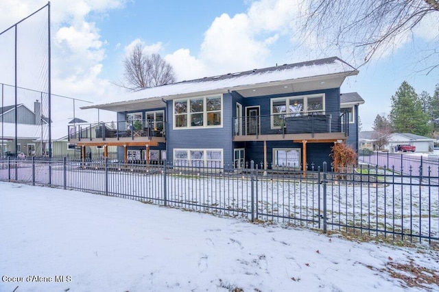 snow covered back of property with a balcony