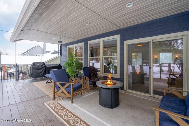 wooden deck with a fire pit and a grill