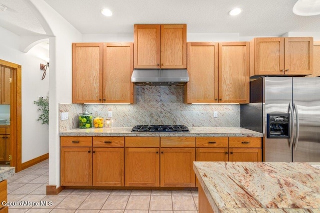 kitchen featuring tasteful backsplash, stainless steel fridge, black gas cooktop, and light tile patterned floors