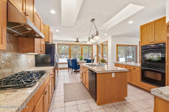 kitchen with black appliances, decorative backsplash, a kitchen island with sink, ceiling fan, and sink