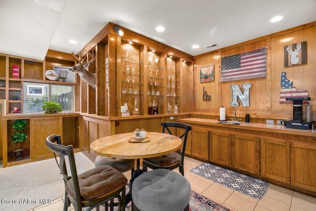 bar featuring wooden walls, light tile patterned floors, and sink