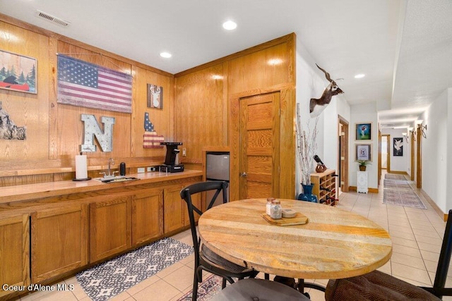 tiled dining area featuring wood walls