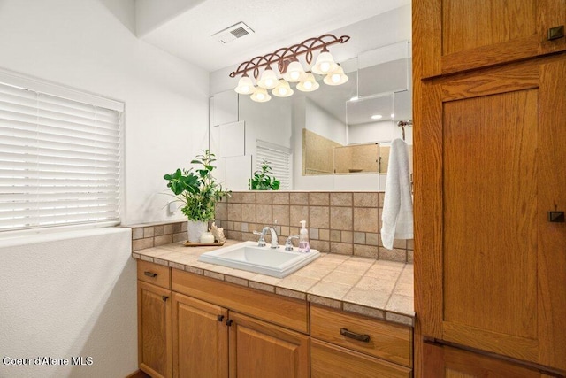 bathroom featuring walk in shower, decorative backsplash, and vanity