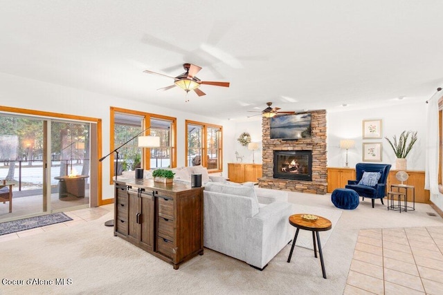 carpeted living room featuring ceiling fan and a stone fireplace