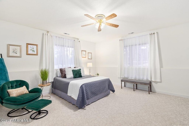 bedroom with ceiling fan, light carpet, and multiple windows