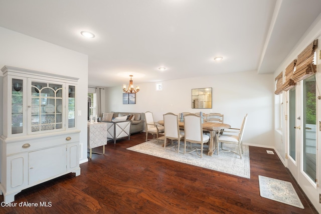 dining space with dark hardwood / wood-style flooring and an inviting chandelier