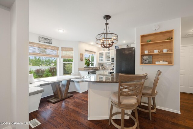 kitchen featuring dark wood-type flooring, white cabinets, black fridge, sink, and kitchen peninsula