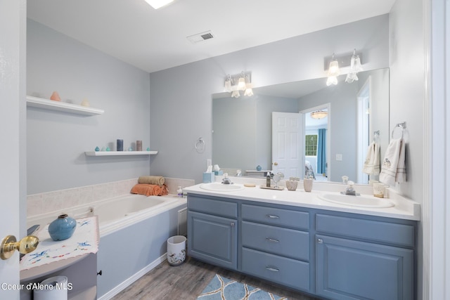 bathroom with vanity, wood-type flooring, and a bath