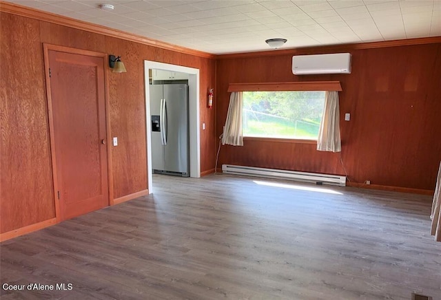 spare room with a wall mounted air conditioner, a baseboard heating unit, crown molding, wood walls, and wood-type flooring