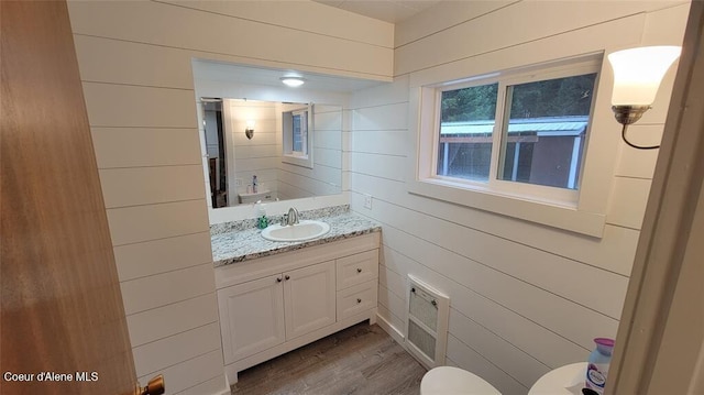 bathroom with vanity, hardwood / wood-style flooring, toilet, and wooden walls