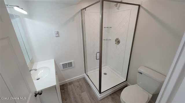 bathroom featuring vanity, toilet, an enclosed shower, and wood-type flooring