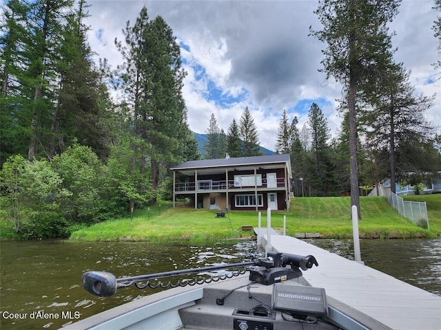 view of dock with a lawn, a water view, and a balcony