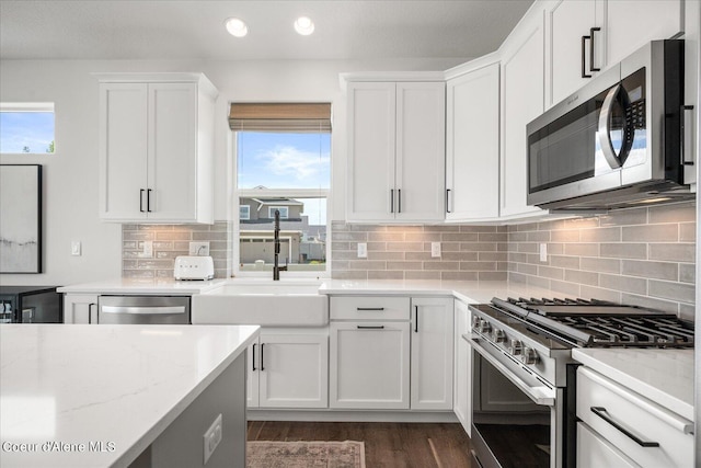 kitchen with white cabinets, light stone counters, and appliances with stainless steel finishes