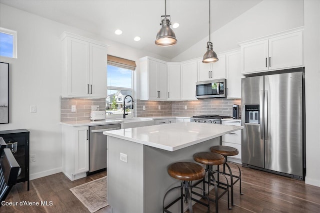 kitchen with sink, a center island, vaulted ceiling, white cabinets, and appliances with stainless steel finishes