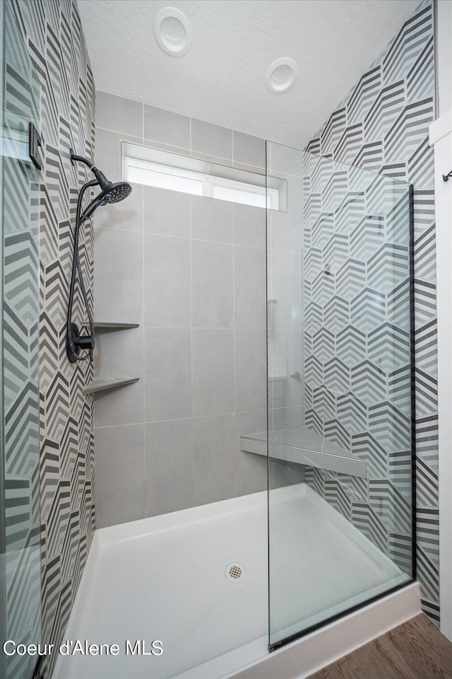 bathroom with a tile shower and wood-type flooring