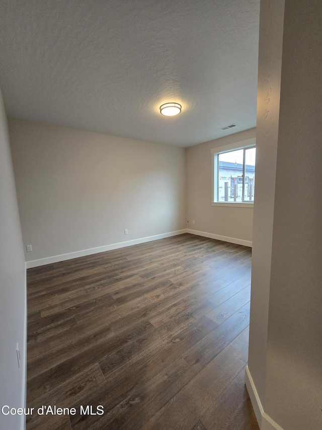 empty room featuring a textured ceiling and dark wood-type flooring