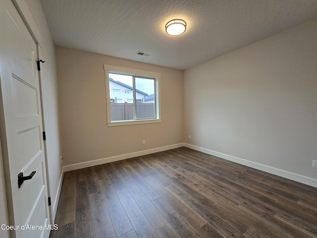 spare room featuring a textured ceiling and dark wood-type flooring