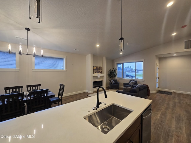 kitchen featuring pendant lighting, dishwasher, sink, vaulted ceiling, and dark hardwood / wood-style flooring