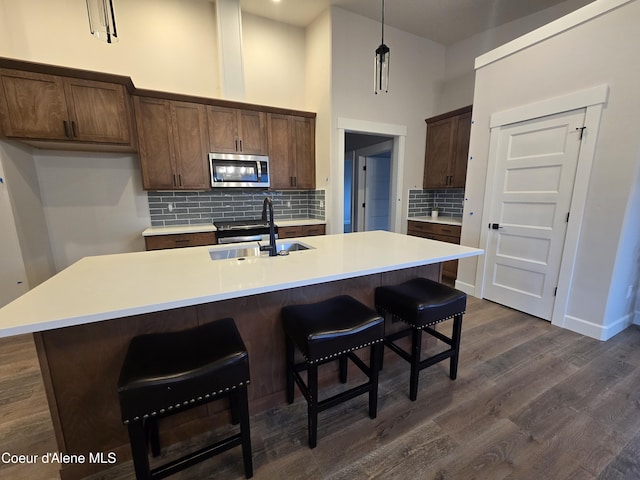 kitchen with a towering ceiling, sink, an island with sink, and pendant lighting