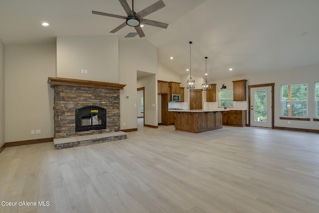 kitchen featuring a center island, a stone fireplace, light hardwood / wood-style floors, and hanging light fixtures