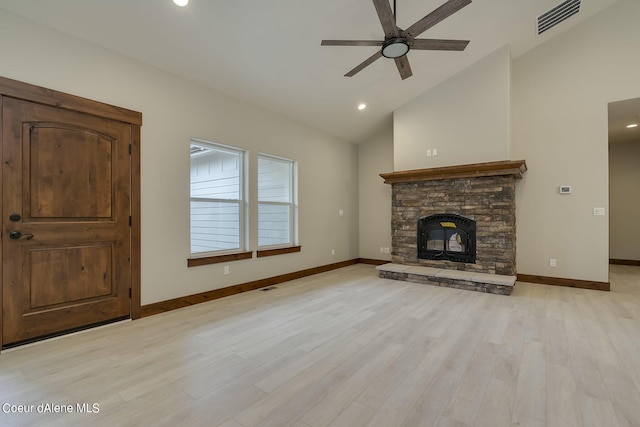 unfurnished living room featuring a wood stove, ceiling fan, vaulted ceiling, and light wood-type flooring