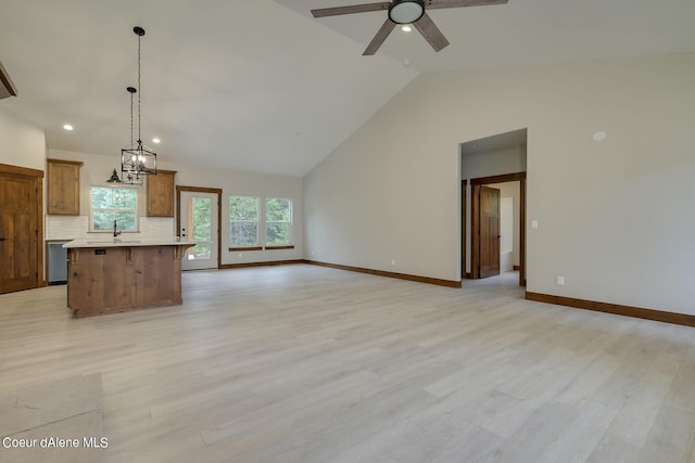 unfurnished living room with ceiling fan with notable chandelier, light hardwood / wood-style floors, and vaulted ceiling