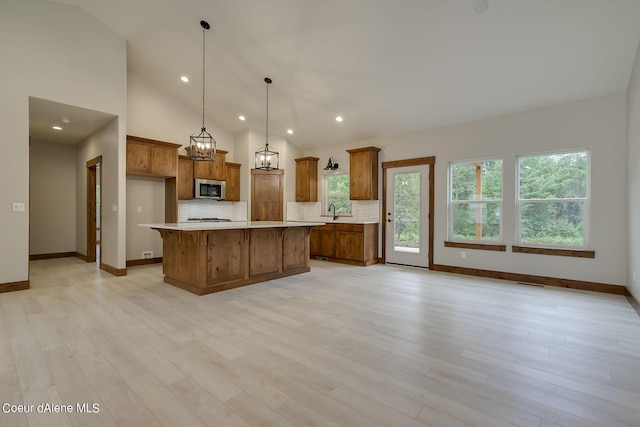 kitchen featuring a center island, sink, tasteful backsplash, light hardwood / wood-style floors, and decorative light fixtures