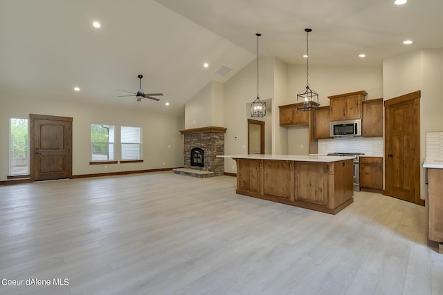 kitchen with tasteful backsplash, stainless steel appliances, ceiling fan, decorative light fixtures, and a center island