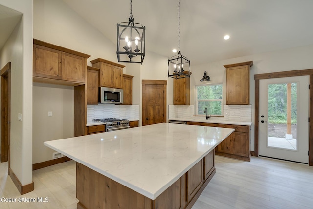 kitchen featuring backsplash, a center island, lofted ceiling, and appliances with stainless steel finishes