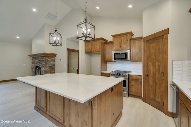 kitchen with backsplash, hanging light fixtures, light hardwood / wood-style flooring, a kitchen bar, and stainless steel appliances