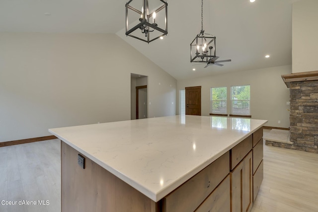 kitchen with light wood-type flooring, a center island, hanging light fixtures, and ceiling fan