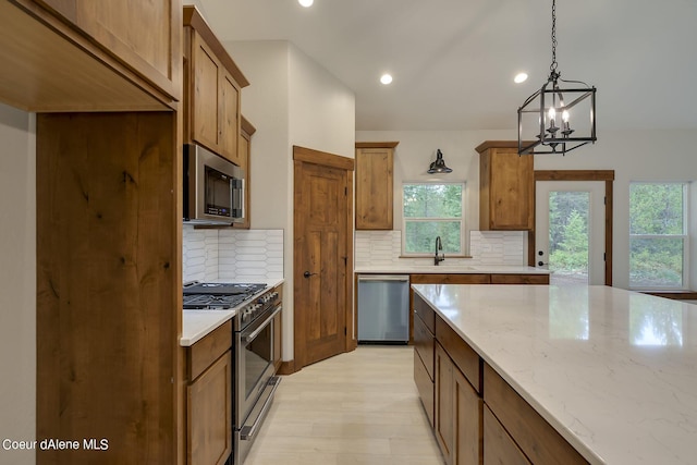 kitchen with stainless steel appliances, tasteful backsplash, light stone counters, a chandelier, and pendant lighting