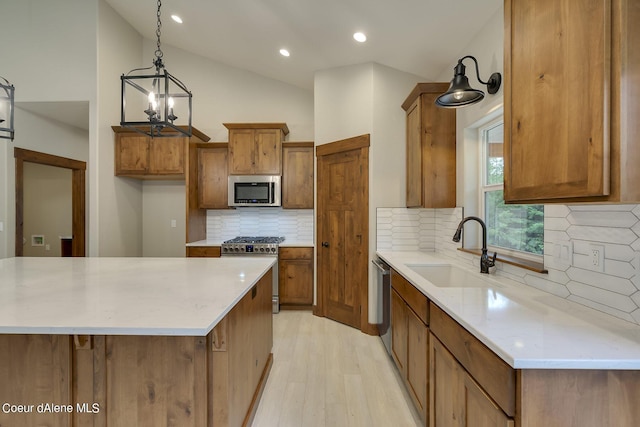 kitchen with sink, vaulted ceiling, tasteful backsplash, decorative light fixtures, and stainless steel appliances