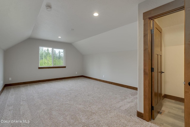 bonus room with light colored carpet and vaulted ceiling