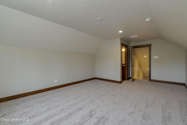 bonus room featuring light carpet, a textured ceiling, and lofted ceiling