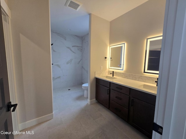 bathroom featuring vanity, toilet, and a tile shower