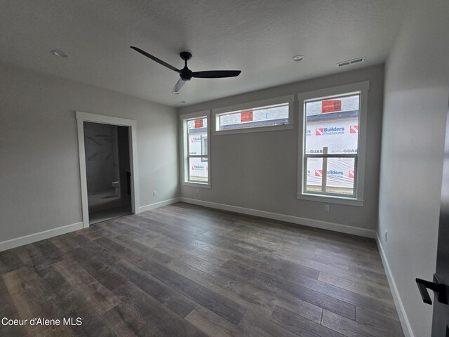 spare room with a textured ceiling, dark wood-type flooring, and ceiling fan