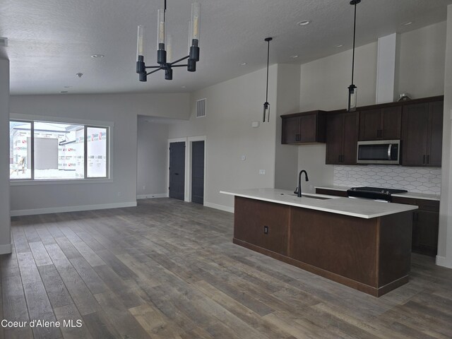 kitchen featuring a kitchen island with sink, sink, pendant lighting, and range